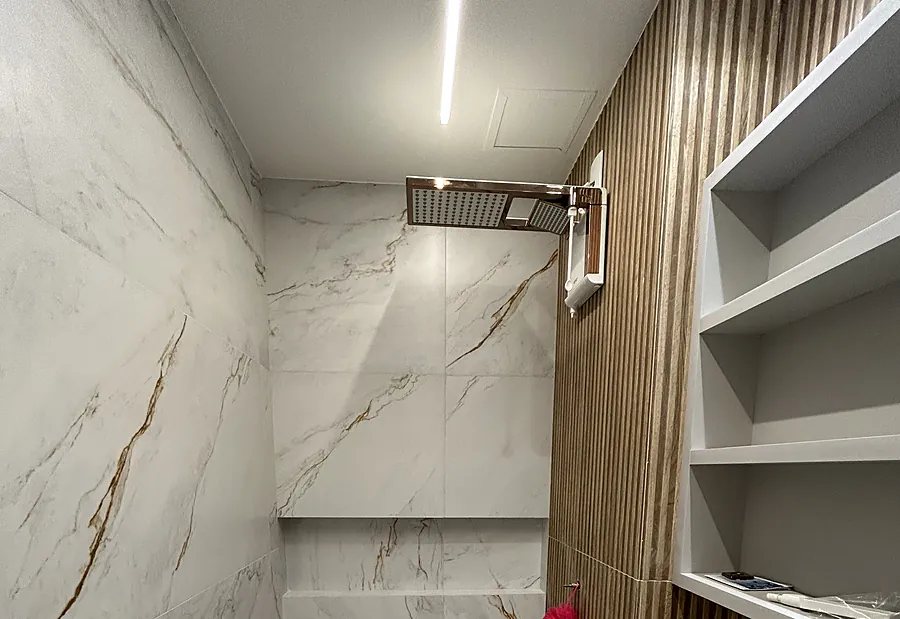 Banheiro com porcelanato marmorizado, nicho e painel ripado em madeira
