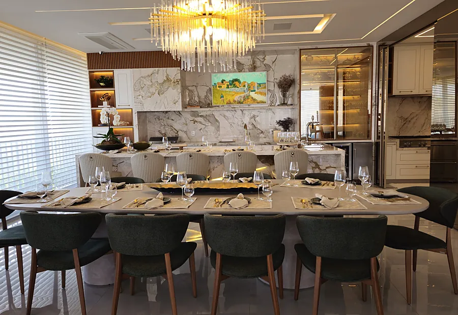 Sala de jantar com painel em pedra, lustre e marcenaria iluminada